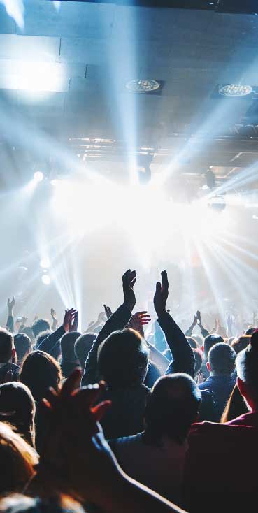 Excited audience cheering under stage lights at an indoor concert at Wvec West Valley Events Complex, Phoenix, Arizona.